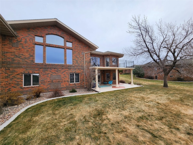 rear view of house featuring a yard, a patio area, and a balcony