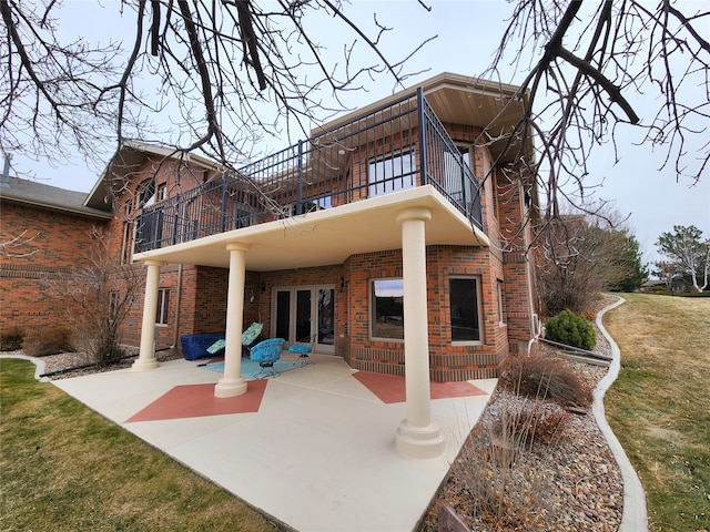 back of property featuring a patio area, a balcony, and french doors