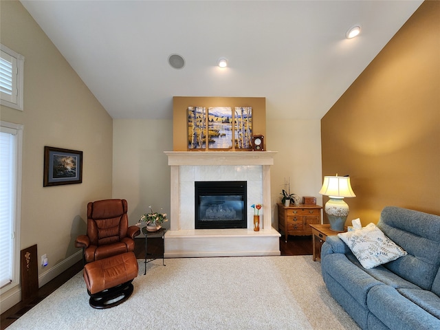 living room with hardwood / wood-style floors, vaulted ceiling, and a tiled fireplace