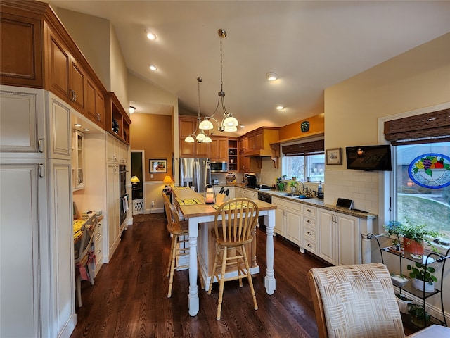 kitchen with stainless steel appliances, a kitchen island, dark hardwood / wood-style floors, and lofted ceiling