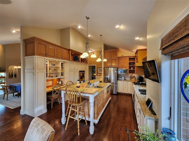 kitchen with appliances with stainless steel finishes, dark hardwood / wood-style flooring, pendant lighting, a center island with sink, and high vaulted ceiling