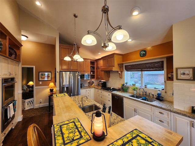 kitchen featuring vaulted ceiling, sink, appliances with stainless steel finishes, and wooden counters