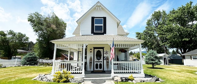 view of front facade with roof with shingles, a front lawn, and covered porch