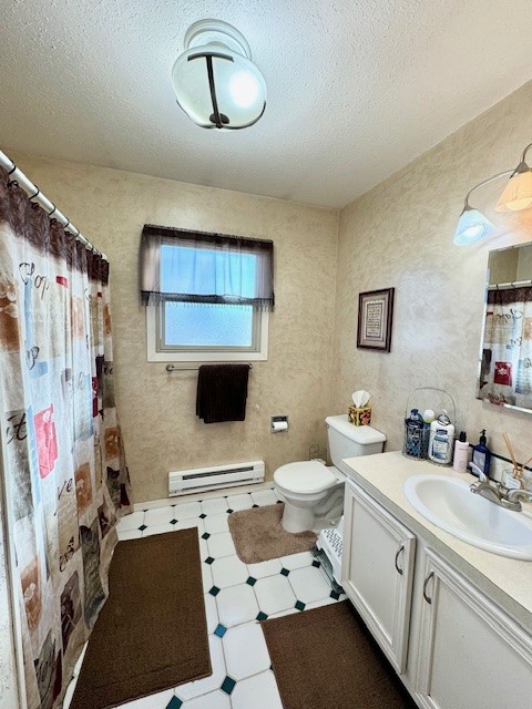 bathroom with a shower with curtain, vanity, a textured ceiling, a baseboard heating unit, and toilet