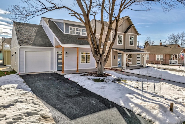 view of front of home featuring a porch, a garage, a shingled roof, driveway, and board and batten siding