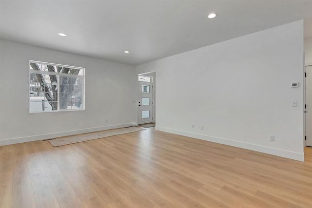 spare room featuring light wood finished floors, recessed lighting, and baseboards