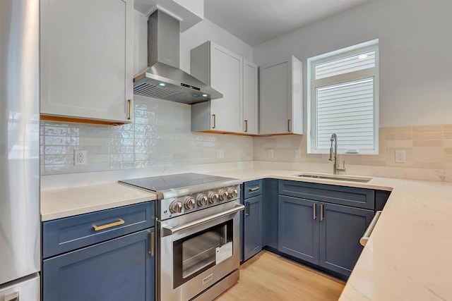 kitchen featuring backsplash, a sink, wall chimney range hood, and high end stainless steel range