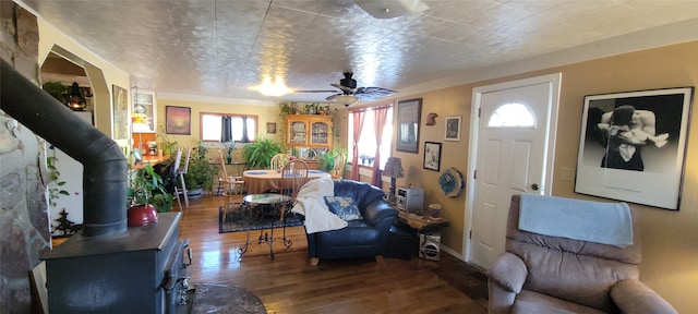 living room featuring a wood stove, ceiling fan, and dark wood-type flooring