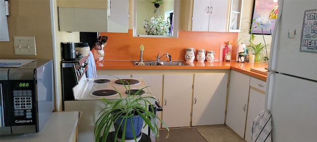 kitchen with white cabinets, light tile patterned floors, white appliances, and sink