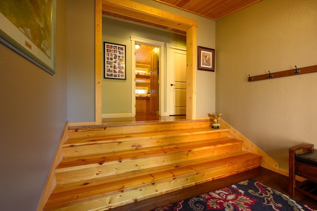 staircase with hardwood / wood-style floors and wooden ceiling