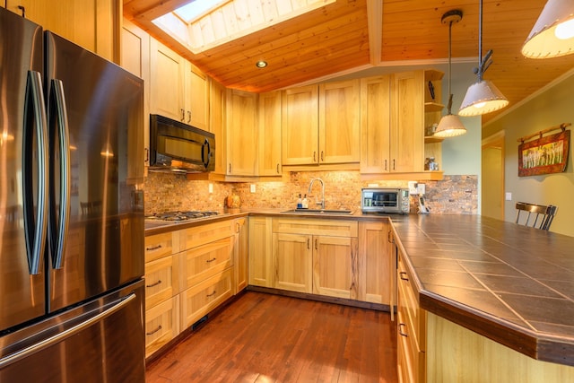 kitchen featuring kitchen peninsula, stainless steel appliances, sink, decorative light fixtures, and dark hardwood / wood-style floors