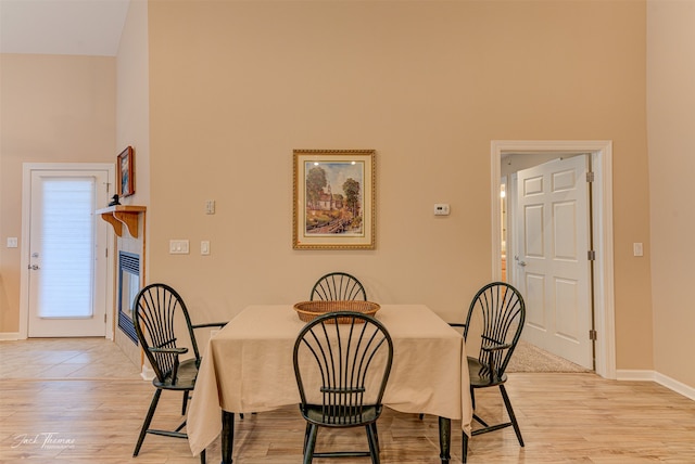 dining space with a towering ceiling and light hardwood / wood-style floors