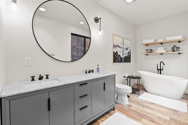 bathroom featuring vanity, toilet, wood-type flooring, and a tub to relax in