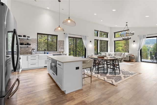 kitchen featuring stainless steel refrigerator, white cabinetry, plenty of natural light, and light hardwood / wood-style floors