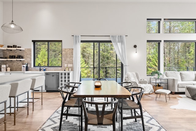 dining space featuring plenty of natural light, light hardwood / wood-style floors, and a towering ceiling