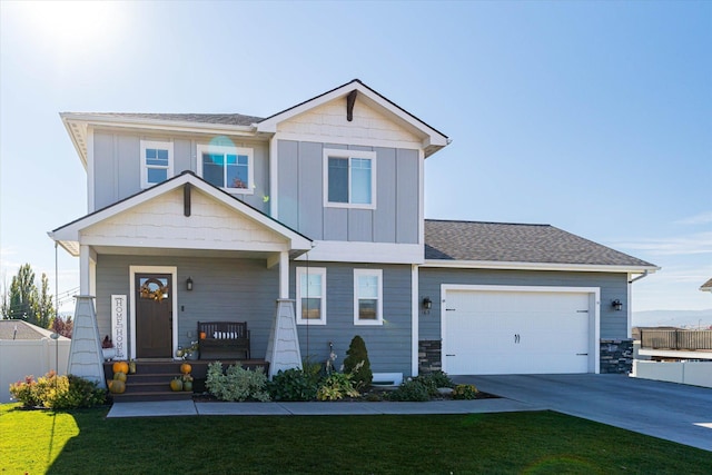 craftsman inspired home featuring a garage, driveway, covered porch, a front lawn, and board and batten siding