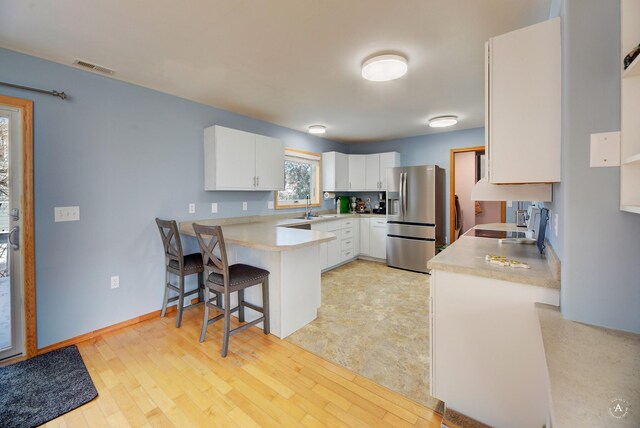 kitchen with kitchen peninsula, white cabinetry, sink, and appliances with stainless steel finishes