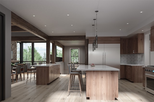 kitchen with decorative light fixtures, a kitchen island, light wood-type flooring, and stainless steel range