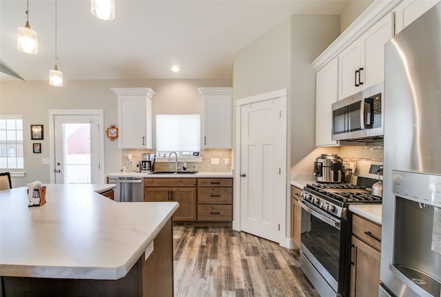 kitchen with white cabinetry, sink, decorative light fixtures, decorative backsplash, and appliances with stainless steel finishes