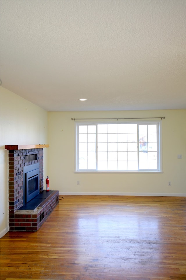 unfurnished living room with a fireplace, wood-type flooring, a textured ceiling, and lofted ceiling