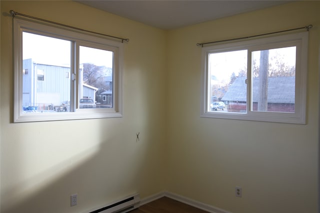 spare room with dark hardwood / wood-style floors, baseboard heating, and a wealth of natural light