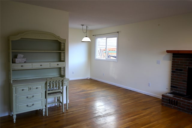 unfurnished dining area featuring dark hardwood / wood-style floors and a brick fireplace