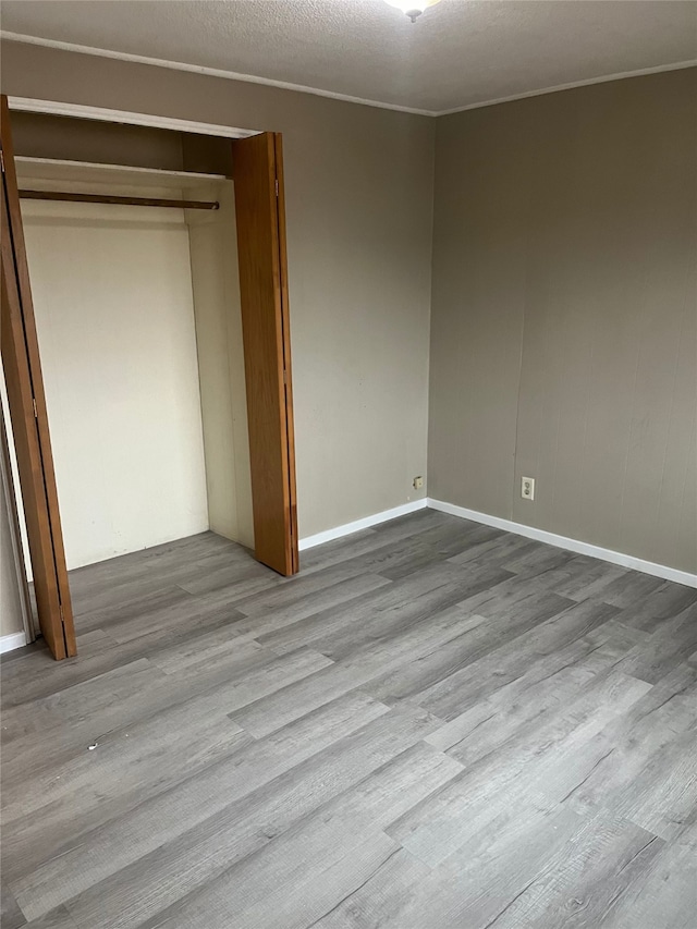 unfurnished bedroom with a closet, ornamental molding, and light wood-type flooring