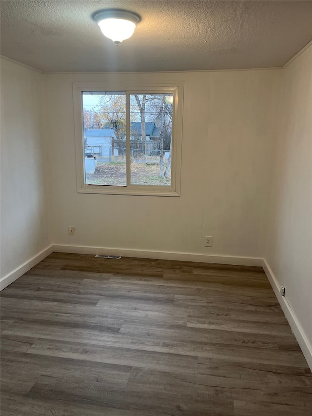 unfurnished room featuring dark hardwood / wood-style flooring and a textured ceiling