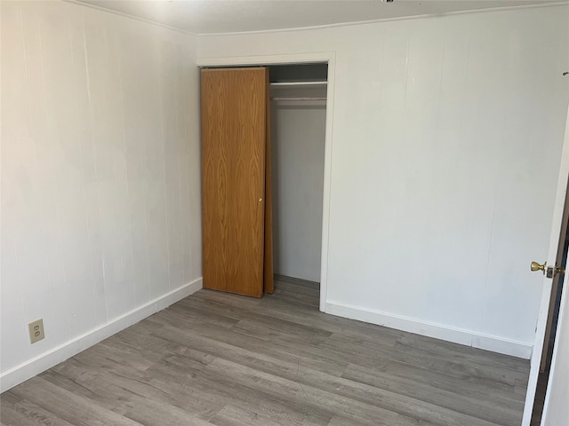 unfurnished bedroom with crown molding, a closet, and light hardwood / wood-style floors