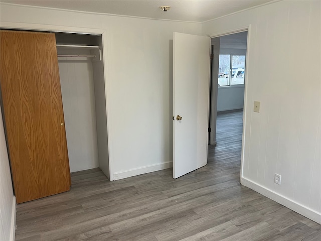 unfurnished bedroom featuring crown molding, a closet, and light hardwood / wood-style floors