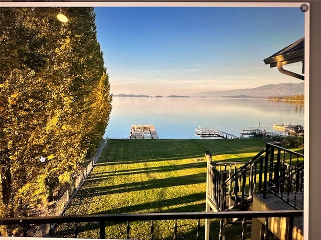 view of dock with a lawn and a water and mountain view