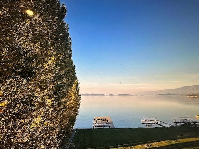 dock area with a water and mountain view and a lawn