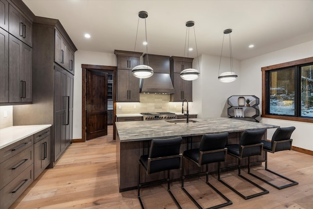 kitchen with a kitchen breakfast bar, sink, light hardwood / wood-style flooring, hanging light fixtures, and a large island