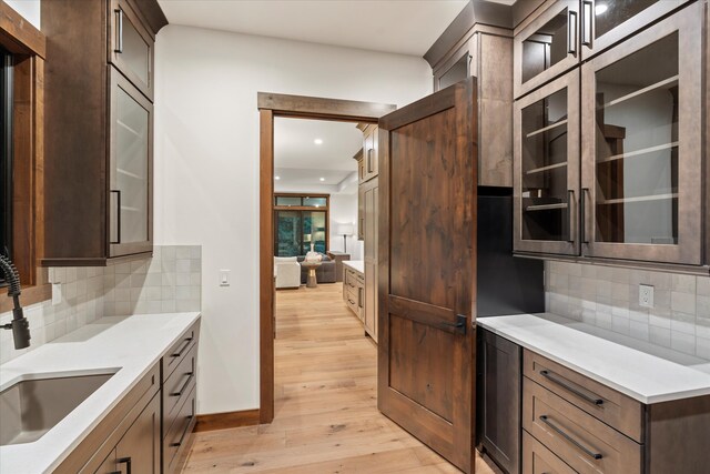 kitchen with decorative backsplash, sink, and light hardwood / wood-style flooring