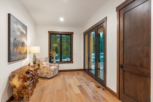 interior space featuring french doors, light hardwood / wood-style floors, and lofted ceiling