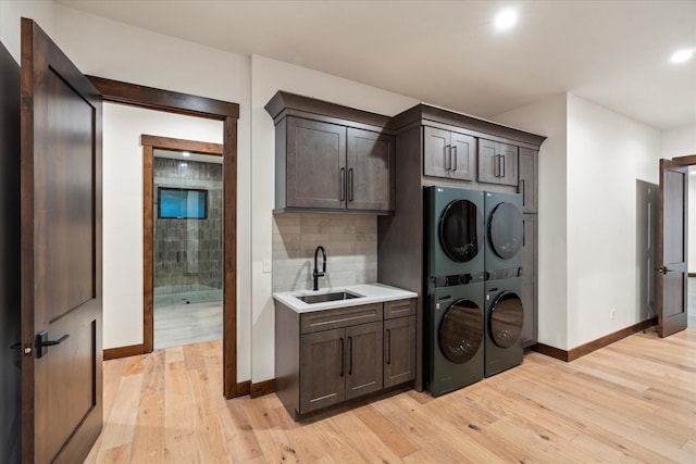 92 Woodlandstar Cir, Whitefish, MT 59937 - laundry room featuring a sink, light wood-style floors, cabinet space, baseboards, and stacked washer and dryer