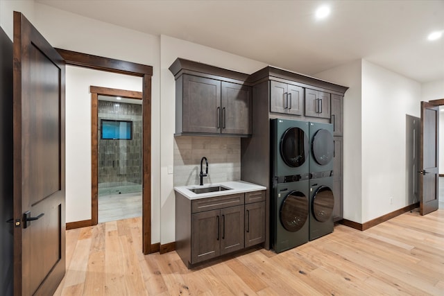 washroom with cabinets, stacked washer and dryer, light hardwood / wood-style flooring, and sink