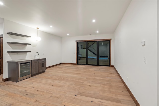 bar with decorative light fixtures, light wood-type flooring, sink, and wine cooler