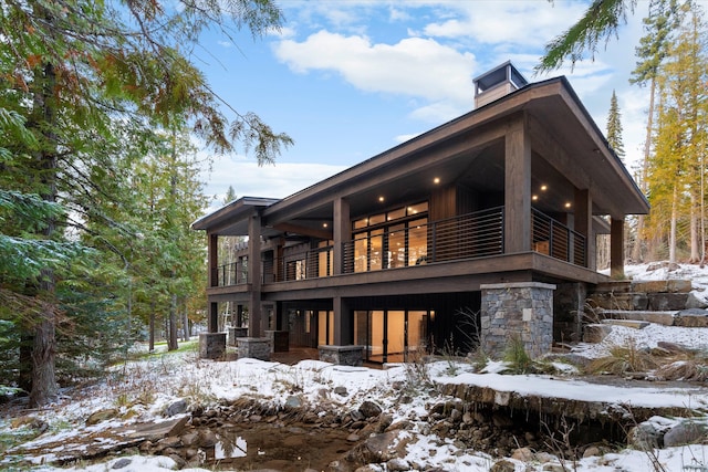 snow covered rear of property with a balcony