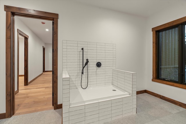 bathroom featuring hardwood / wood-style flooring and tiled tub