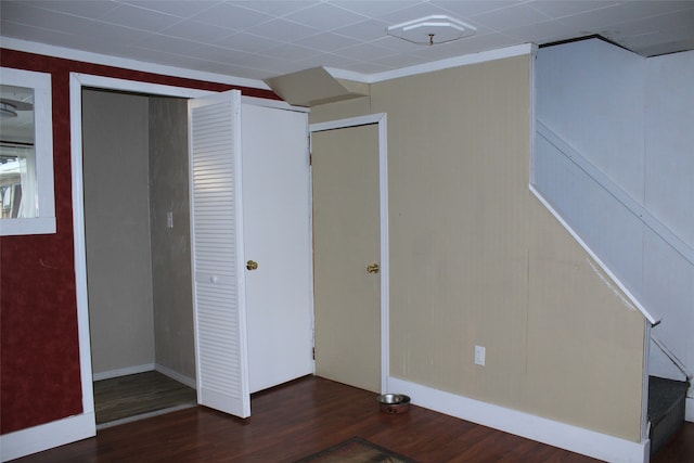 unfurnished bedroom with crown molding, a closet, and dark wood-type flooring