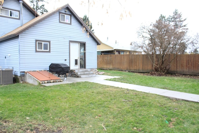 rear view of property featuring a yard and central AC