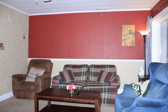 living room with carpet floors, ornamental molding, and brick wall