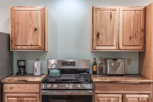 kitchen with stainless steel gas stove and light brown cabinets