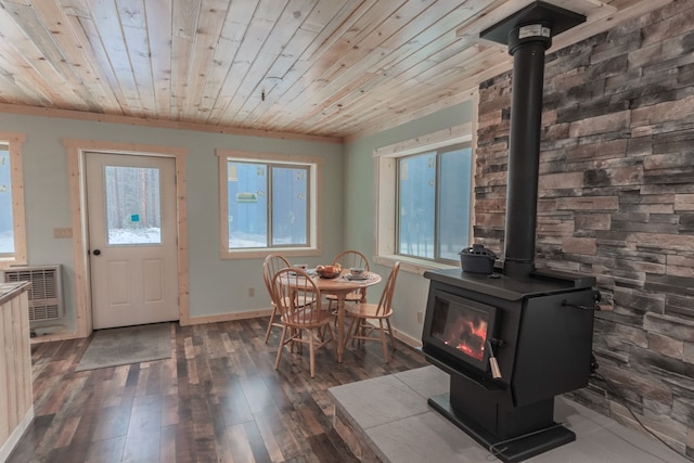 dining room with a wall mounted air conditioner, dark hardwood / wood-style floors, a wood stove, and wooden ceiling