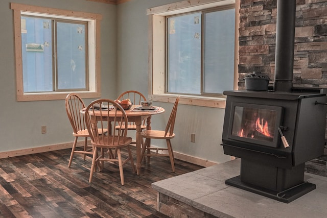 dining space with a wood stove, plenty of natural light, and dark hardwood / wood-style flooring