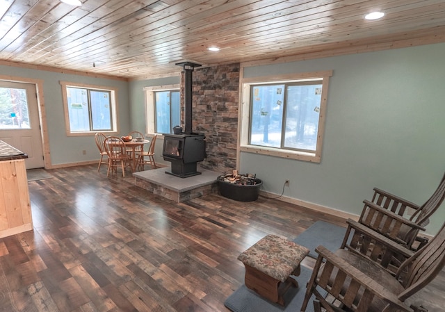 living room with dark hardwood / wood-style floors, a wood stove, and wooden ceiling