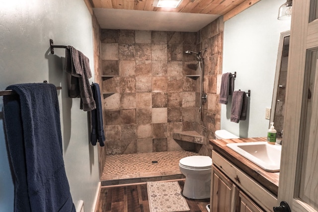 bathroom with wooden ceiling, wood-type flooring, tiled shower, toilet, and vanity