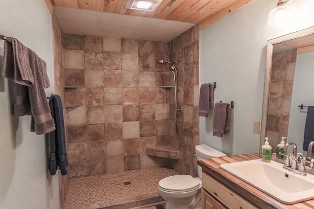 bathroom with a tile shower, vanity, and toilet