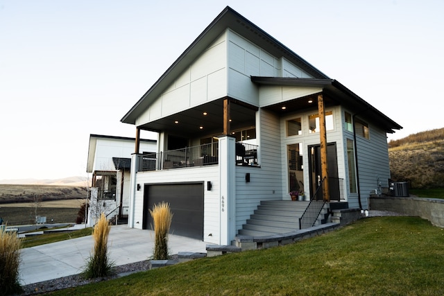 view of front of property featuring a balcony, a front yard, and a garage